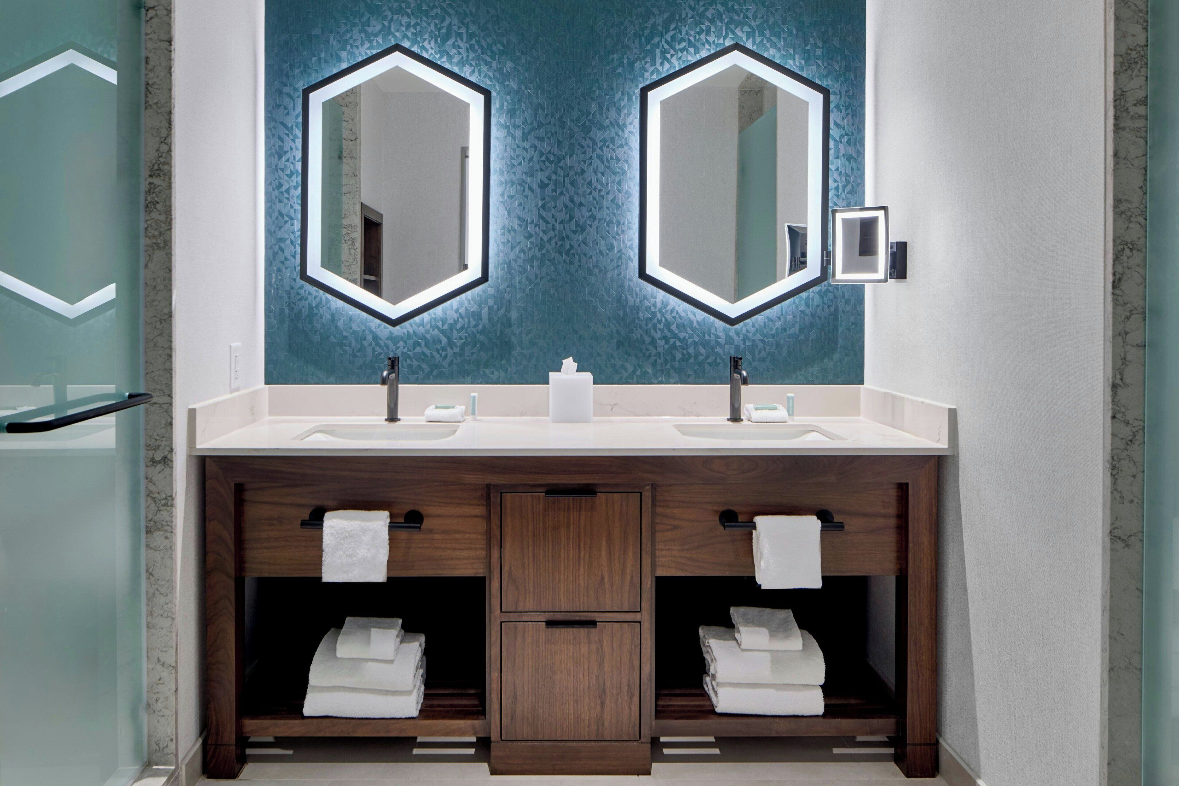 Une salle de bain moderne avec deux vasques, des meubles en bois et un mur bleu à texture.