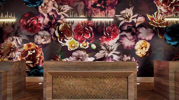 A reception area with a floral mural, a wooden reception desk, and a patterned wall design.