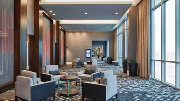 A hotel lobby with seating areas, a patterned carpet, and large windows.