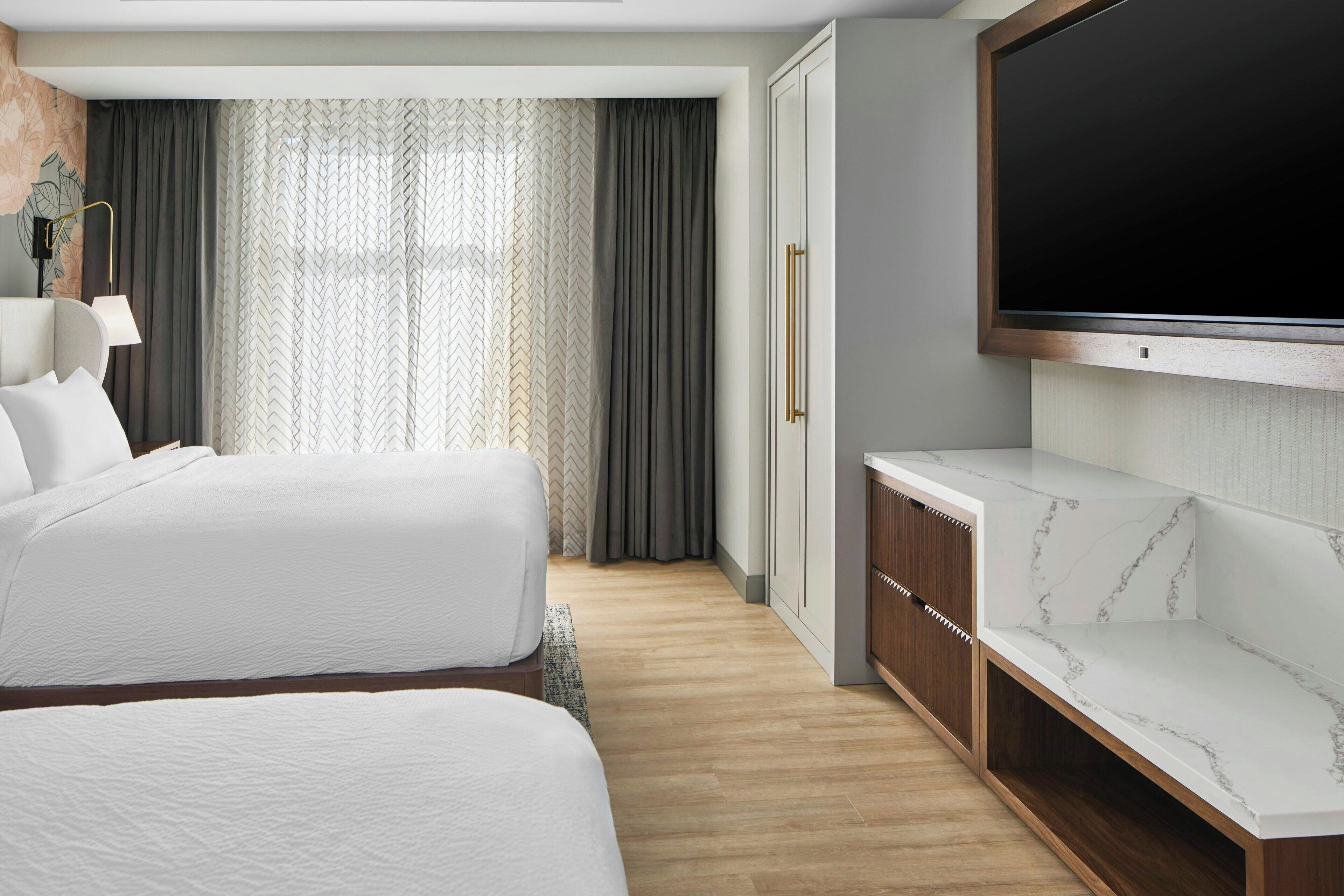 Une chambre d’hôtel avec deux lits, une télévision, un bureau et une armoire.