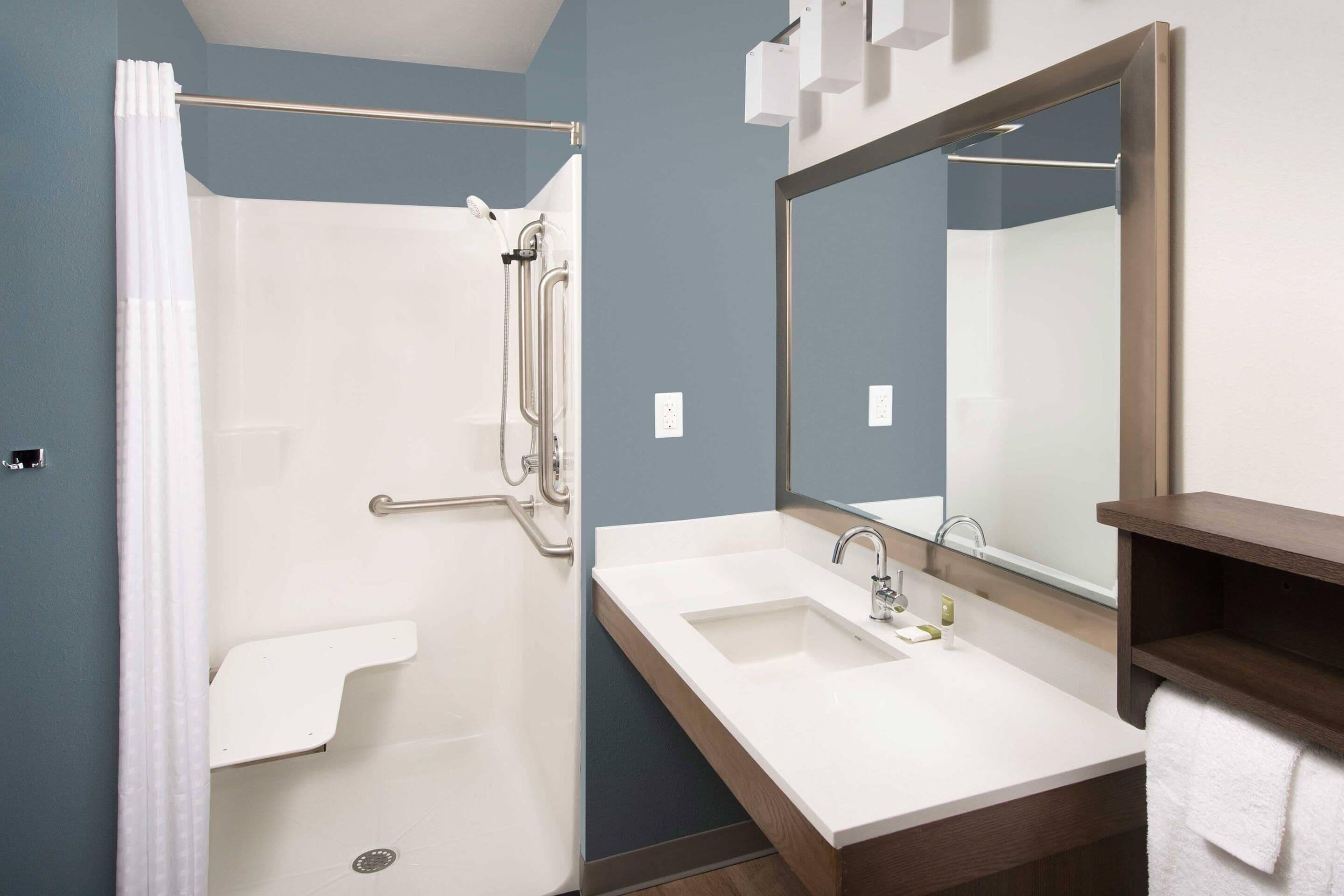 Un baño moderno con ducha, lavamanos y espejo.