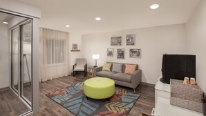 A modern living room with a sofa, ottoman, and a flat-screen TV.