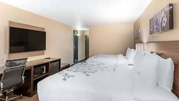 Habitación de hotel con una cama grande, un escritorio con televisor de pantalla plana, un microondas y una silla.