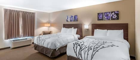 A hotel room with two beds, a large window with curtains, a wall-mounted air conditioner, and two wall-mounted lamps.