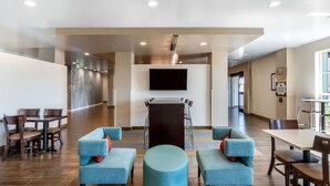 A modern hotel lobby with a large flat-screen TV, comfortable seating, and a wooden reception desk. - Sleep Inn & Suites Denver International Airport (Denver)
