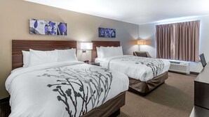 A hotel room with two beds, a desk, a chair, a lamp, and a window with curtains. - Sleep Inn & Suites Denver International Airport (Denver)