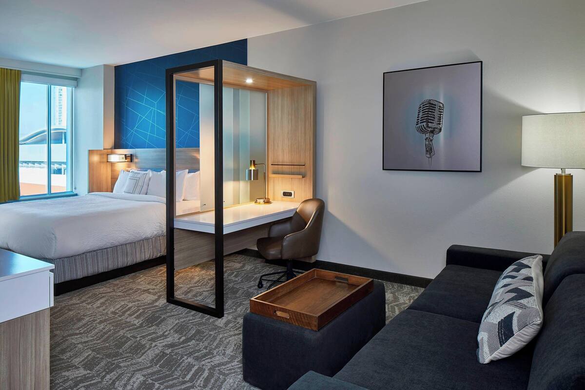 Une chambre d’hôtel avec un lit, un bureau, une chaise et un canapé.
