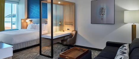A hotel room with a bed, desk, chair, and a sofa.