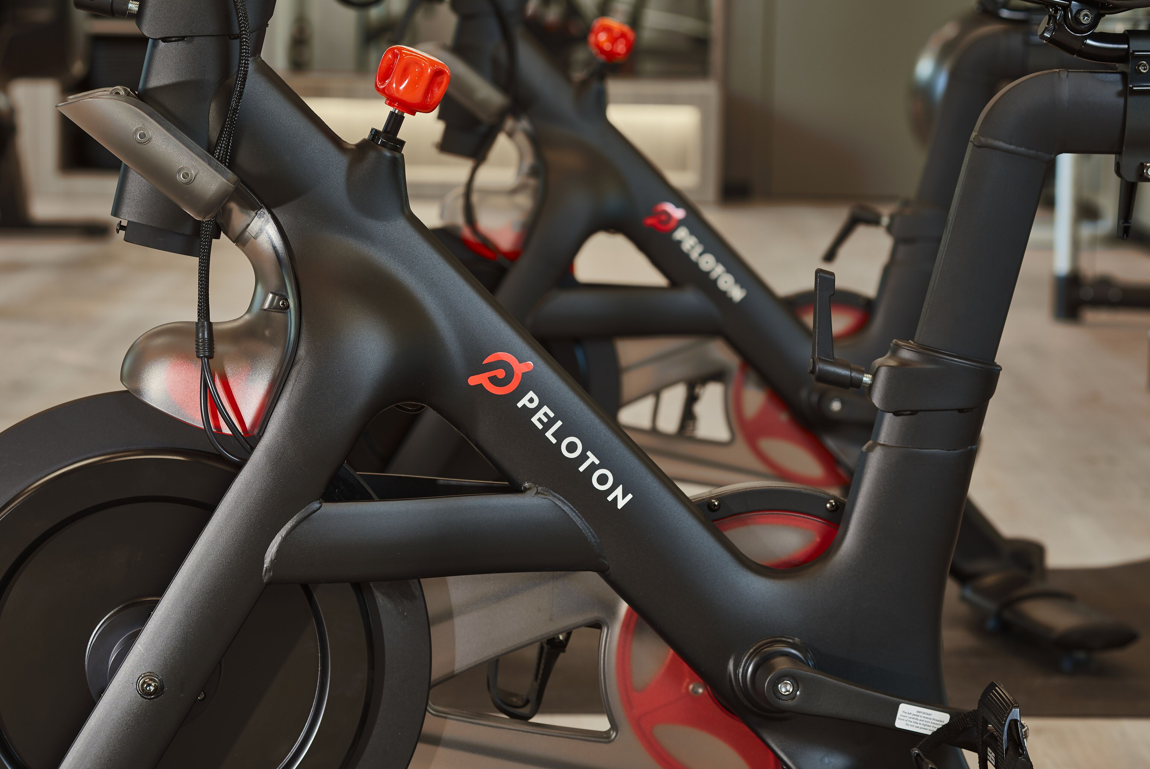 Un vélo d’appartement dont le cadre porte clairement la marque « PELOTON ».
