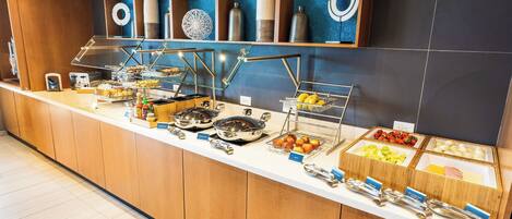 A buffet counter with various food items and utensils.