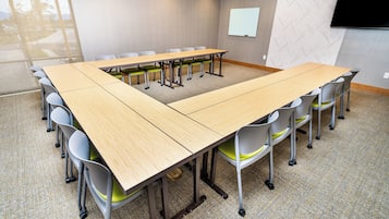 Un salón de conferencias con una gran mesa y sillas, una pizarra y un televisor en la pared.