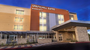Un hotel moderno con un letrero grande que dice "Springhill Suites Marriott" y una zona de entrada cubierta.