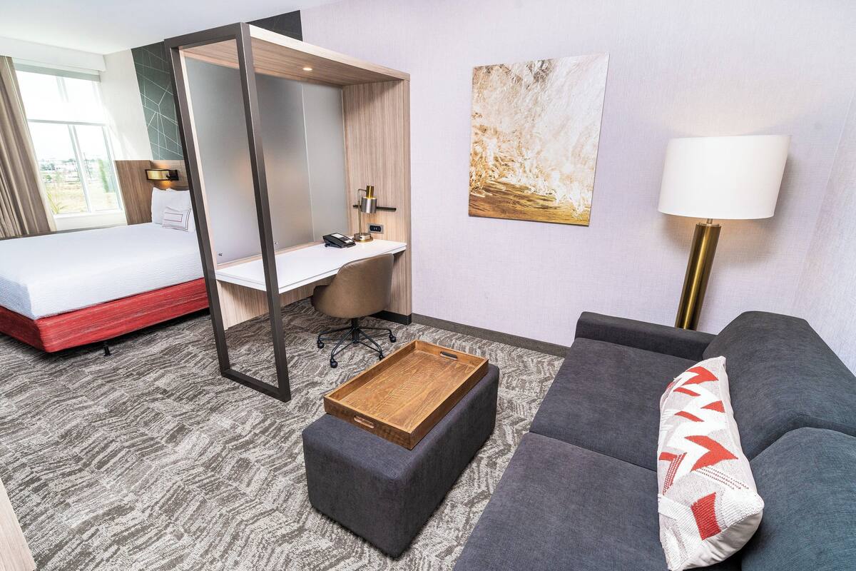 Ein Hotelzimmer mit Bett, Schreibtisch, Sofa und einem kleinen Holztisch.