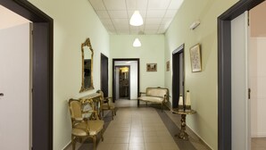 A hallway with a light green wall, a chandelier, and a mirror. There are two chairs and a small table with a vase. - City center house in Rhodes (Rhodes)