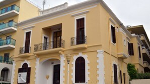A yellow building with white trim, multiple balconies, and arched windows. - City center house in Rhodes (Rhodes)