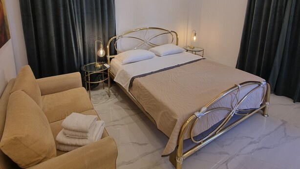 A modern bedroom with a bed, bedside tables, a sofa, and curtains. - City center house in Rhodes (Rhodes)
