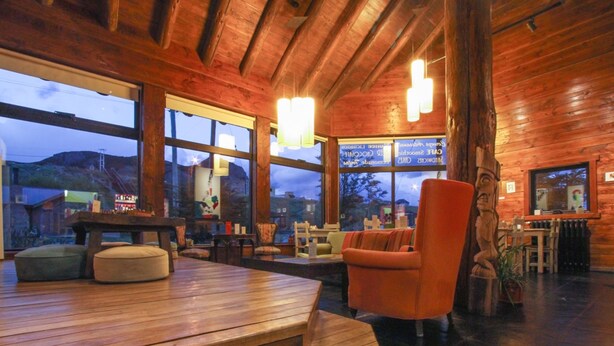 A cozy wooden interior with a large window, a wooden bench, and a red chair. - Kaulem Hotel Boutique (El Chalten)