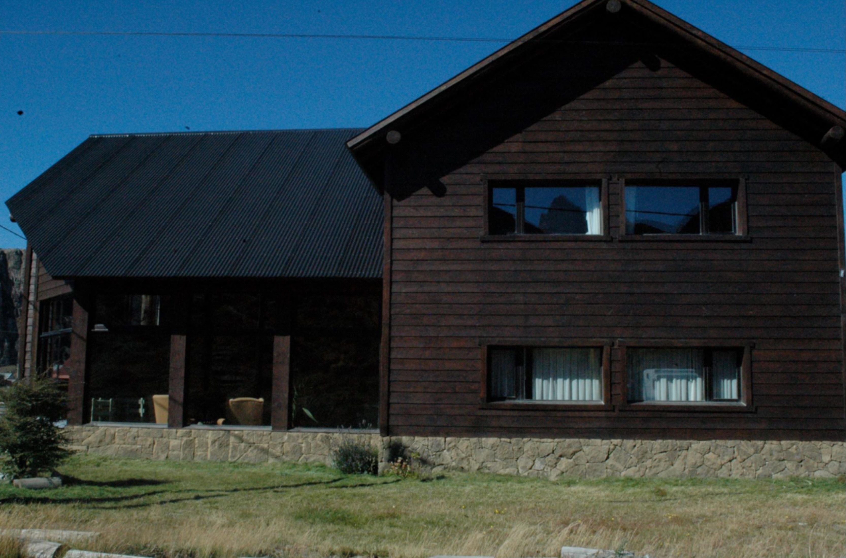 A two-story wooden house with a sloped roof and large windows.