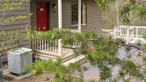 A small house with a red door, a porch, and a white railing. - Creekside Village (Basye)