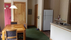 A compact kitchen with a wooden dining table and chairs, a refrigerator, and a sink. - Creekside Village (Basye)