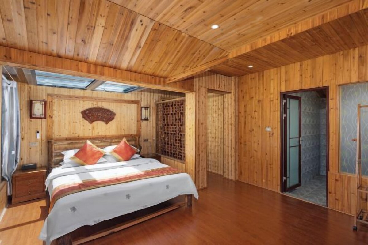 A wooden-paneled room with a bed, a wall-mounted decorative piece, and a door leading to another room.