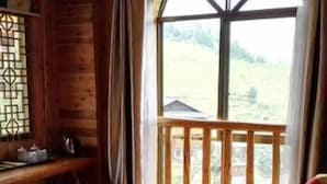 A wooden cabin room with a bed, a window with a view of the outdoors, and a wooden railing. - Li Ru Yododo Villa (Guilin)