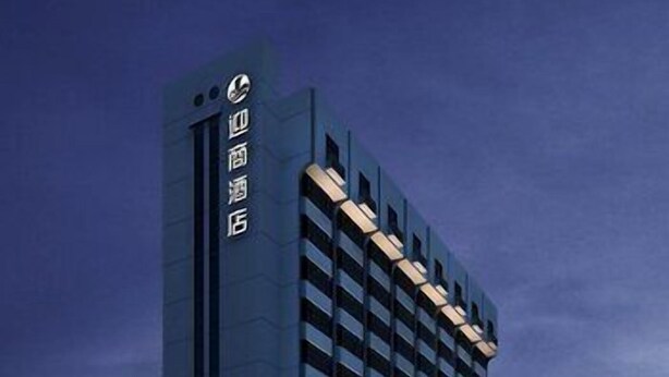 Un edificio moderno e slanciato con un design architettonico distintivo, caratterizzato da un grande cartello verticale con scritte.