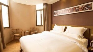 Una camera d'albergo con un letto grande, una scrivania, due sedie e un quadro appeso al muro.