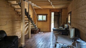 Interno di una baita in legno con una scala, una scrivania, un fornello e una poltrona in pelle nera.