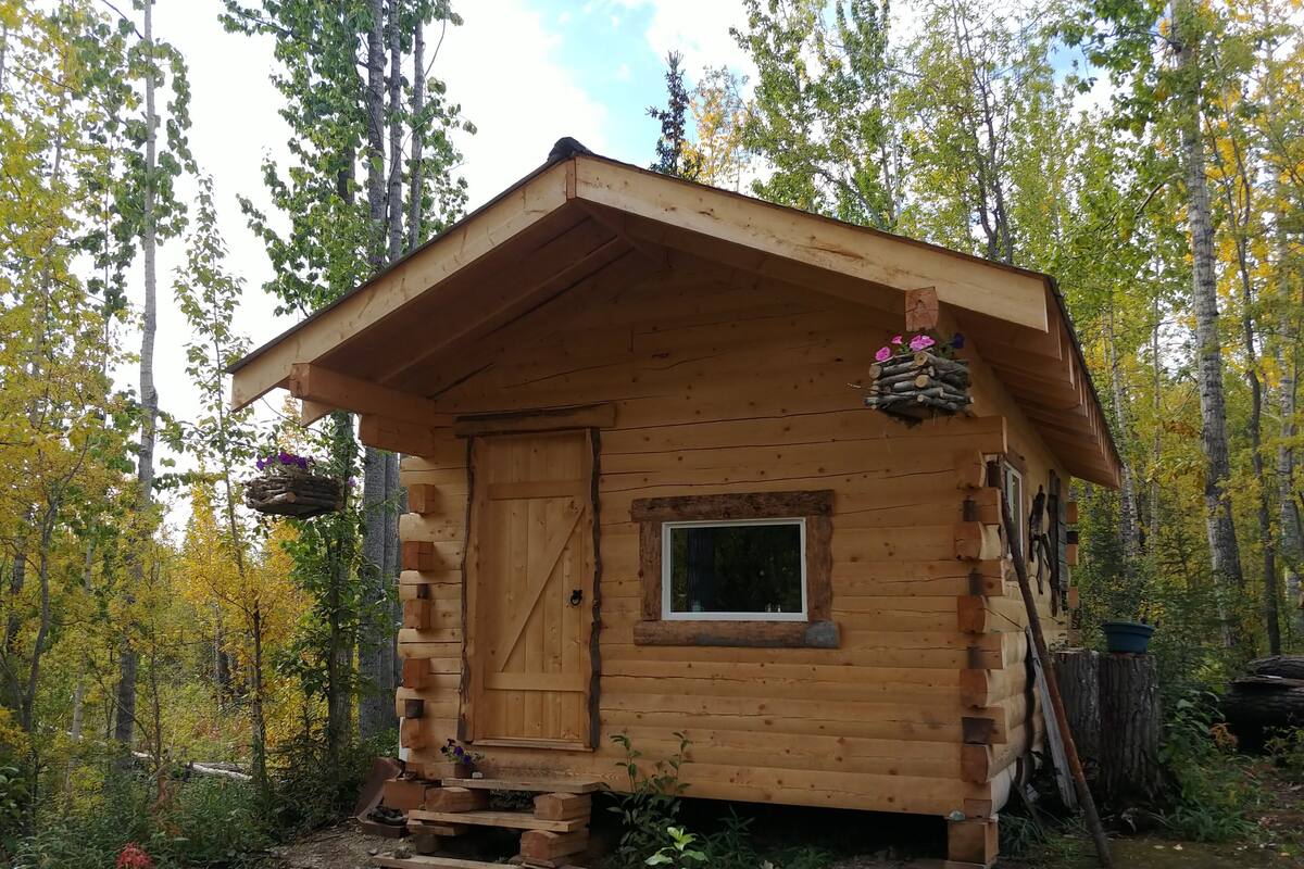 Une petite cabane en bois avec une porte d’entrée, une fenêtre et une véranda.