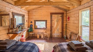 Un accogliente chalet con pareti in legno, una zona notte soppalcata, una cucina con lavello e fornelli, e una finestra con vista sull'esterno.