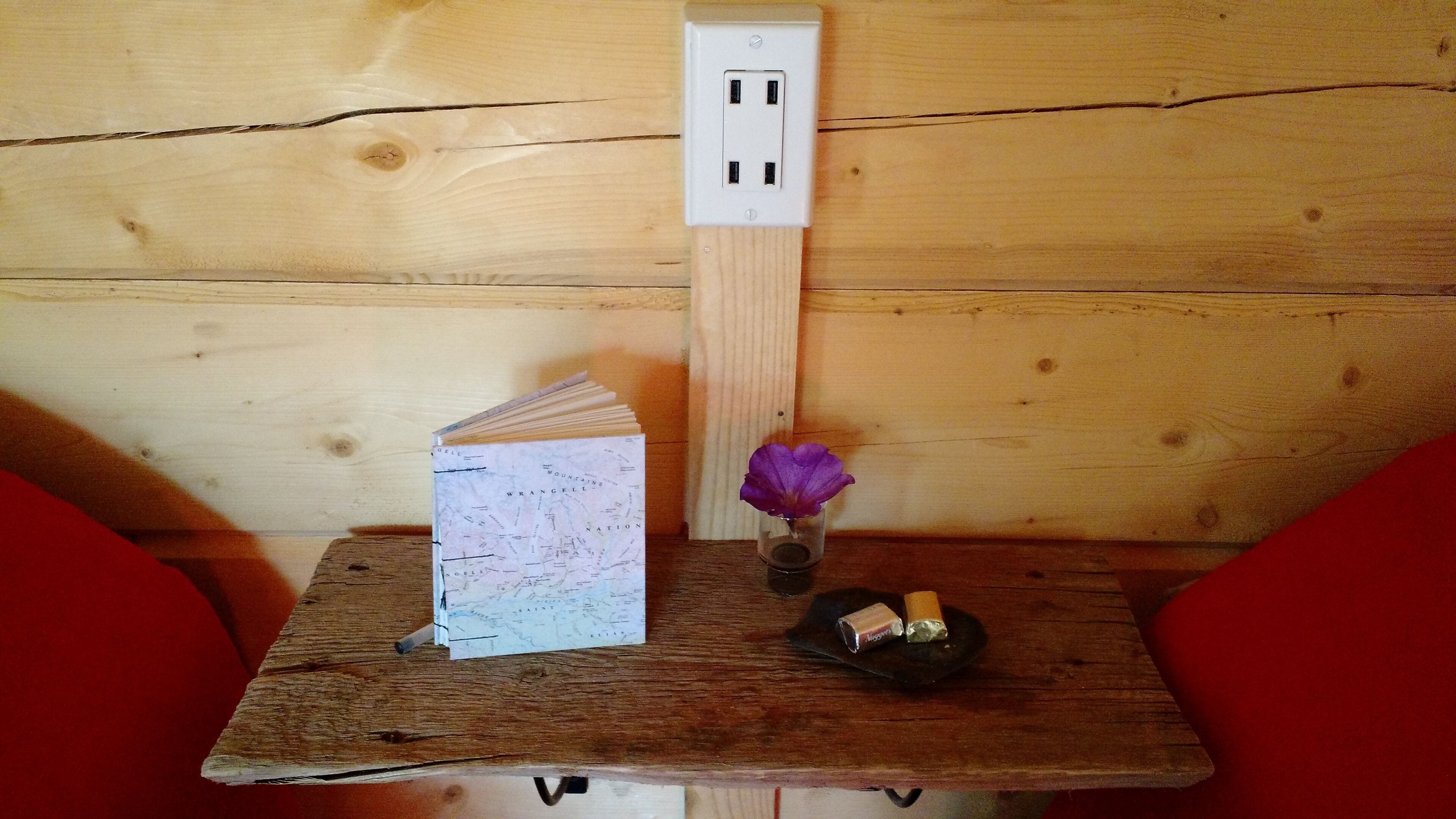 A wooden table with a map, a candle, and a purple flower in a glass.