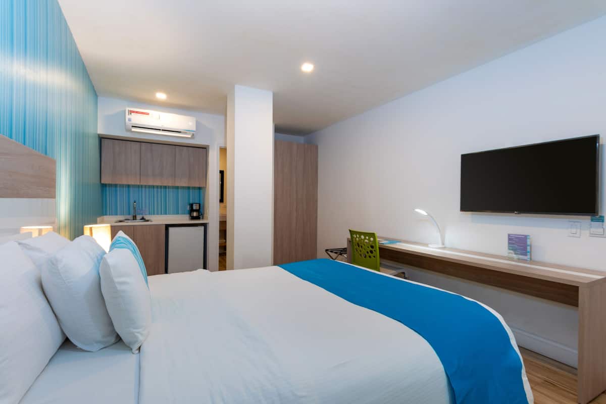 Une chambre d’hôtel équipée d’un lit, d’un bureau, d’une chaise, d’une télévision et d’un appareil de climatisation.