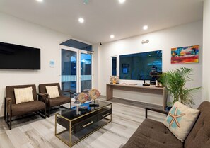 Ein modernes Wohnzimmer mit Flachbildfernseher, bequemen Sitzmöglichkeiten, einem Couchtisch und einem großen Fenster mit Blick.