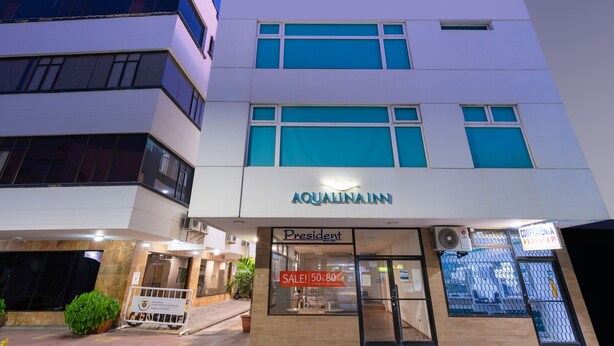 Un hotel llamado AQUALINAIN, con un letrero que dice 'President', un anuncio de oferta y una entrada con portones.