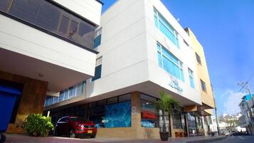 A modern building with a large glass storefront, a red car parked in front, and a clear blue sky.