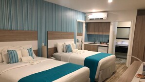 Una habitación de hotel con dos camas, kitchenette y baño.