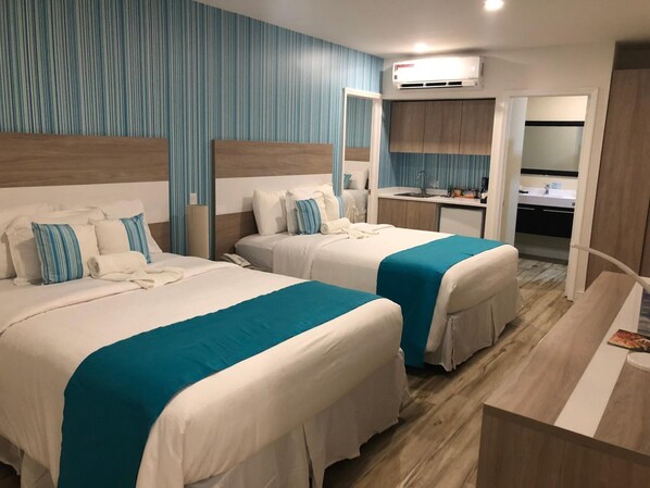 Hotellihuone, jossa on kaksi sänkyä, pieni keittiö ja kylpyhuone.