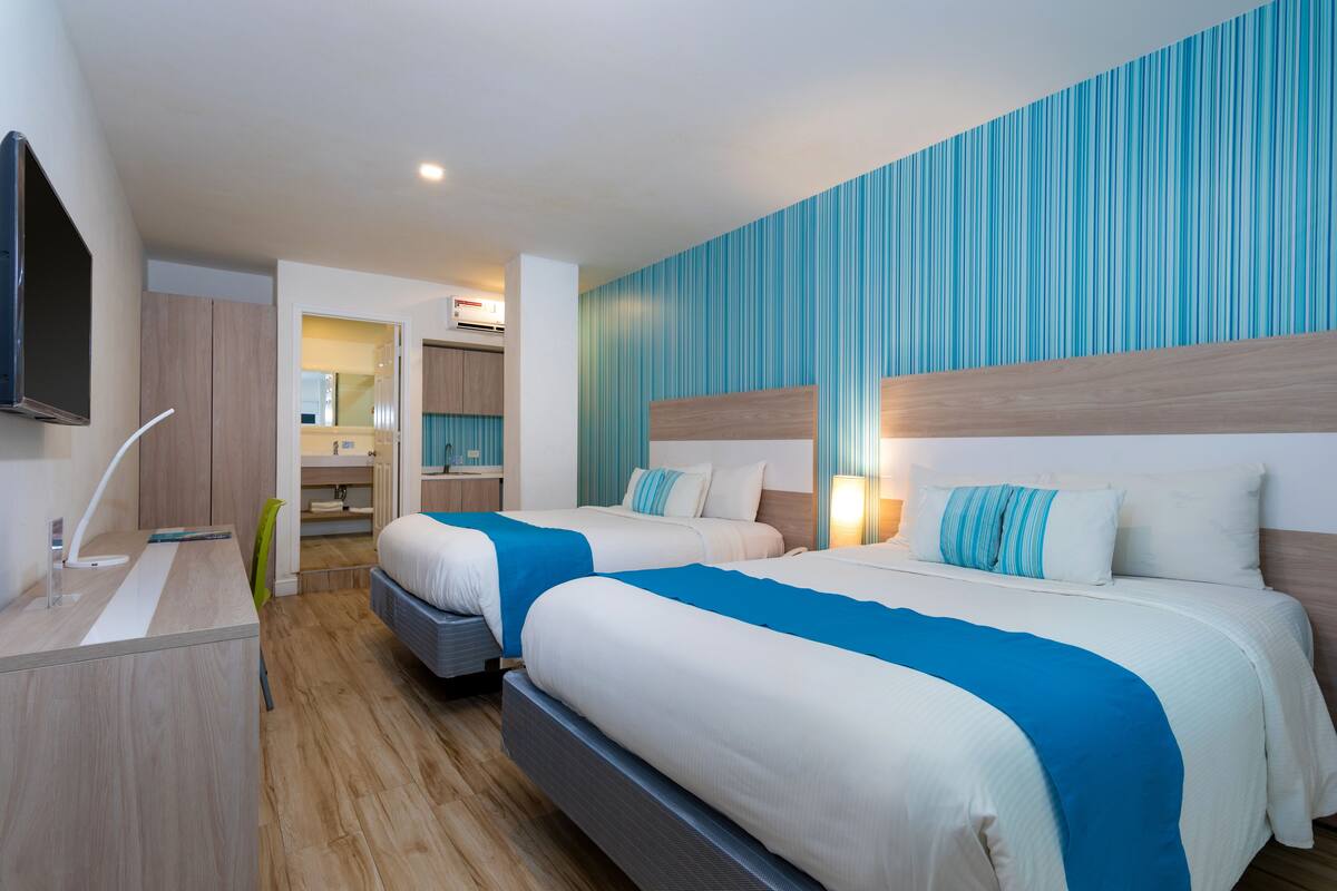 Une chambre d’hôtel avec deux lits, un bureau, une chaise et un téléviseur.