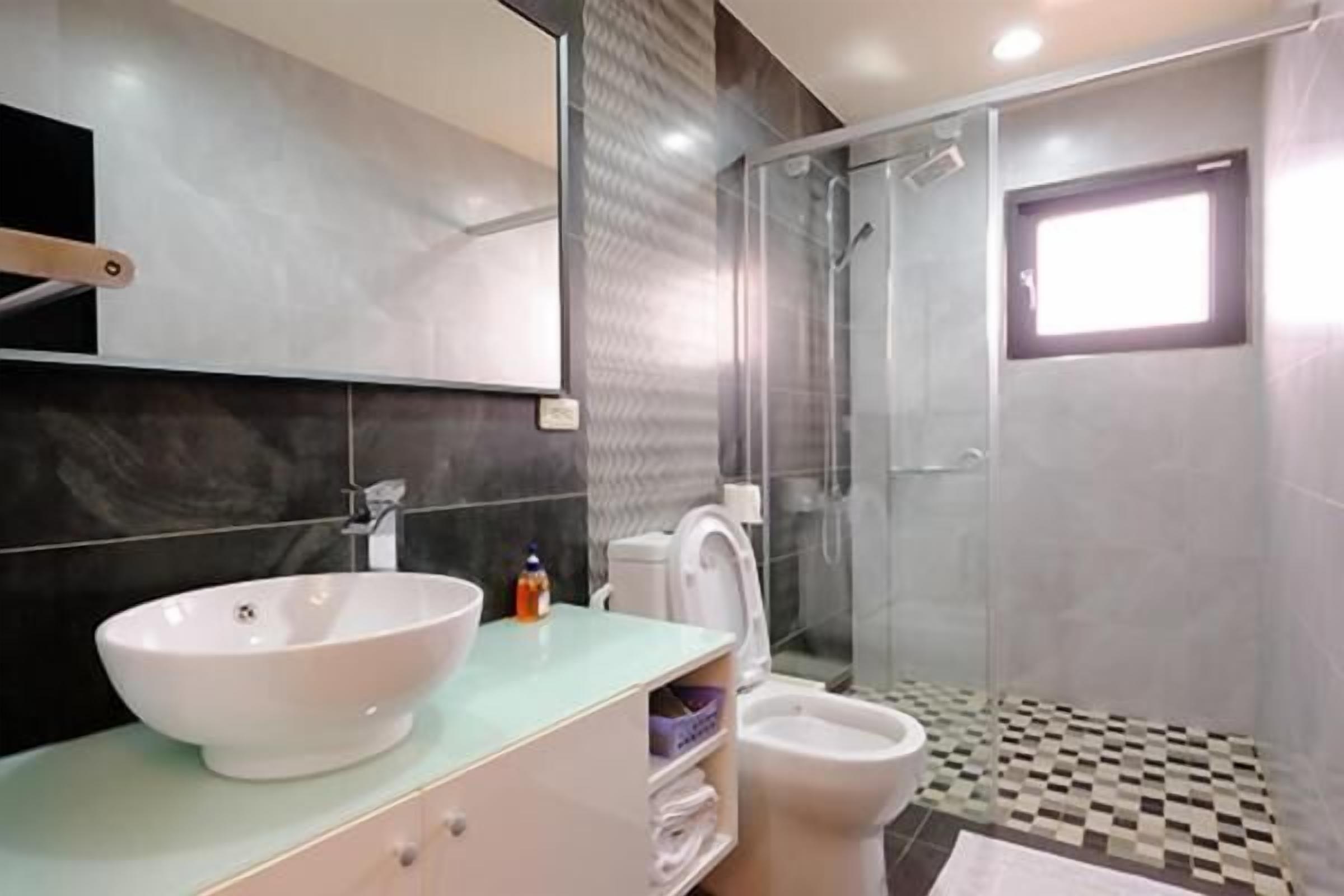 Une salle de bain moderne avec un grand lavabo blanc, une douche en verre et des toilettes.