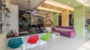 Una cocina moderna con una isla central, un área de comedor con un sofá púrpura y una sala de estar con una silla verde.