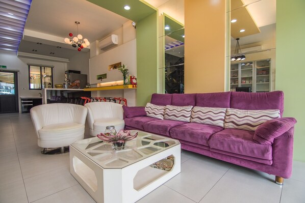 A modern living room with a purple sofa, white armchairs, and a glass coffee table. - Little Skylark B&B (Magong)