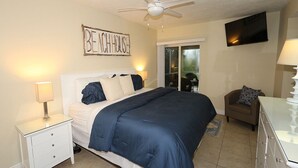 Une chambre à coucher comprenant un lit, une table de chevet, une commode et un ventilateur de plafond.