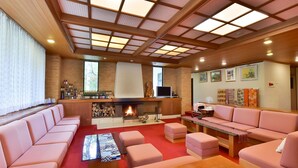 A modern living room with a fireplace, a bar area with bottles, and a large window. - Fudoson-no-Yu Oyado Kotobuki (Yamanouchi)