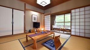 A traditional Japanese room with tatami flooring, a low wooden table, a television, and sliding doors leading to a balcony with a view of greenery. - Fudoson-no-Yu Oyado Kotobuki (Yamanouchi)
