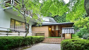 A modern building with a brick facade, large windows, and a green entrance area. - Fudoson-no-Yu Oyado Kotobuki (Yamanouchi)