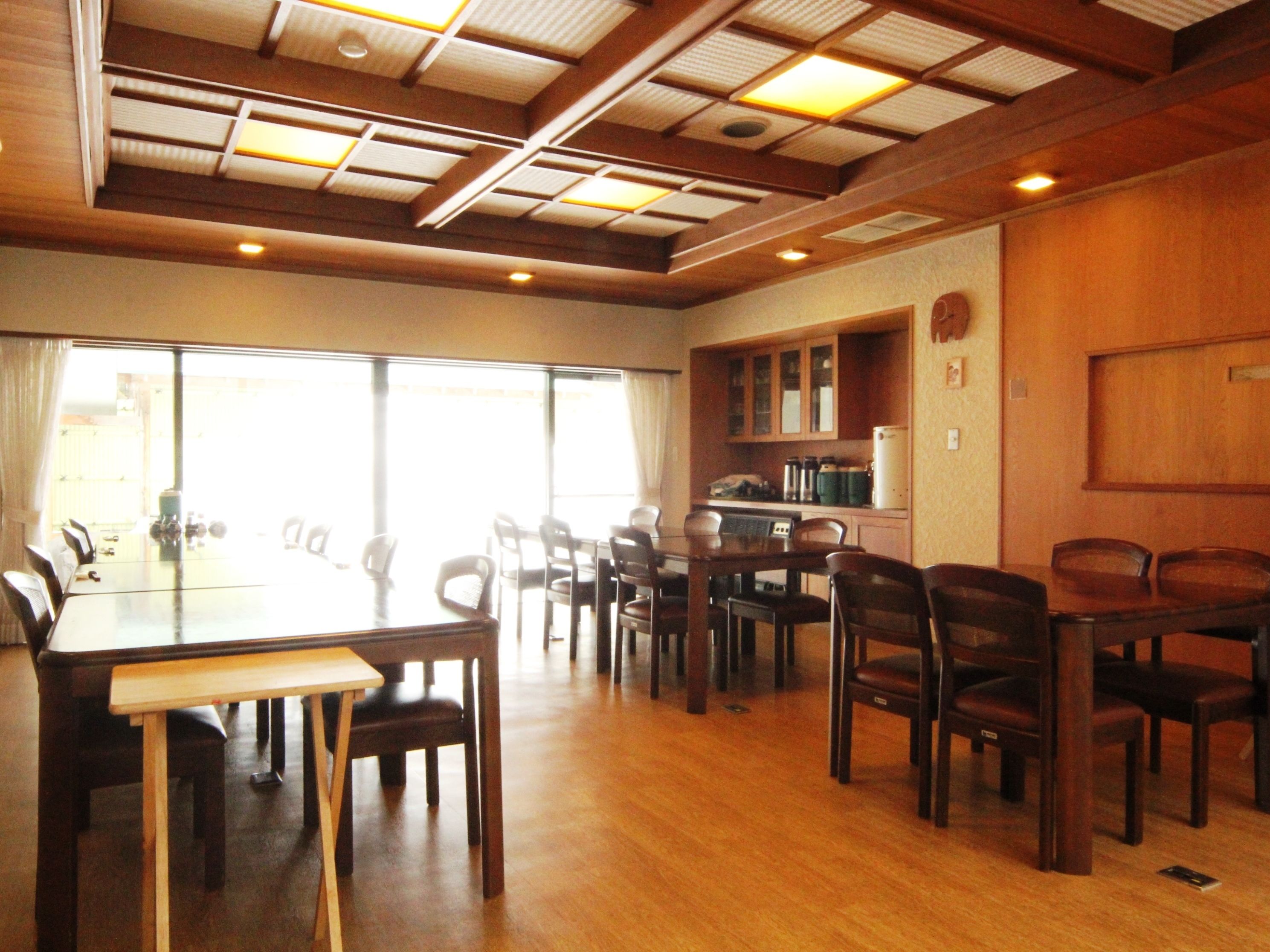 A conference room with a large table and chairs, wooden paneling, and a view through large windows.