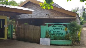A bamboo bungalow with a sign indicating rooms for rent, including air-conditioned and non-air-conditioned options, free WiFi, and an enquiry inside. - Alona Bamboo House (Panglao)