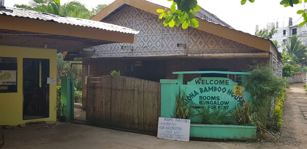 A bamboo bungalow with a sign indicating rooms for rent, including air-conditioned and non-air-conditioned options, free WiFi, and an enquiry inside. - Alona Bamboo House (Panglao)