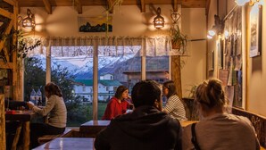 A cozy restaurant with wooden beams and large windows offering a view of snow-capped mountains.